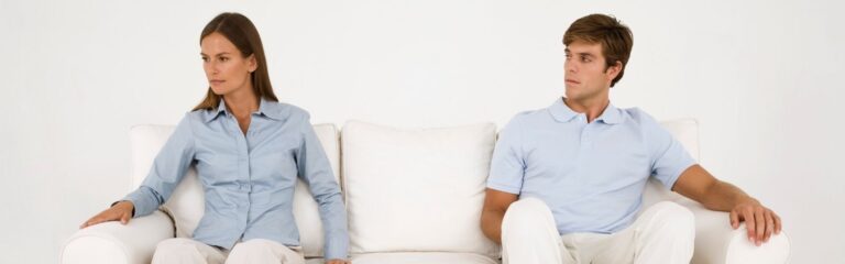 marido y mujer enfadados sentados cada uno en un extremo de un sofá