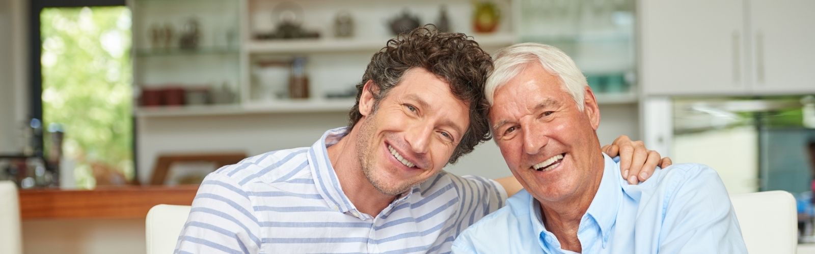 fotografía de un hijo adulto sonriente junto a su padre que también sonríe a la cámara