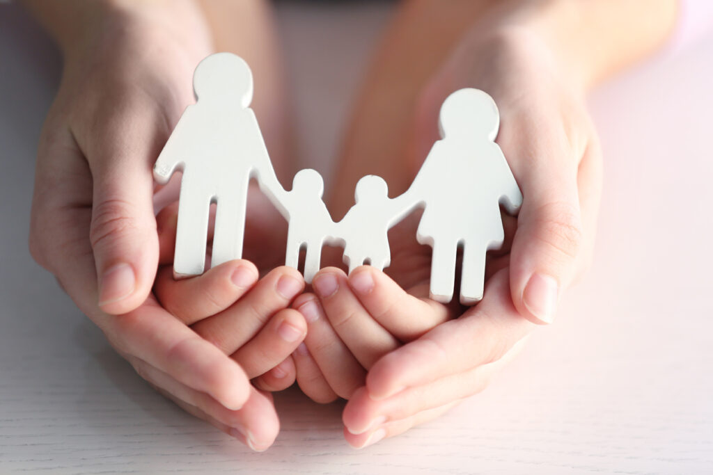 manos que sostienen la silueta de una familia feliz