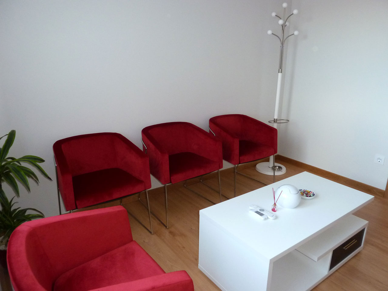 sala de espera del despacho de abogados EAR de Mos donde se ve una mesita blanca en primer plano y butacas confortables de color rojo